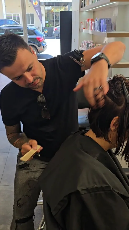 Stylist mid-cut on a client's dark hair at Vanity salon