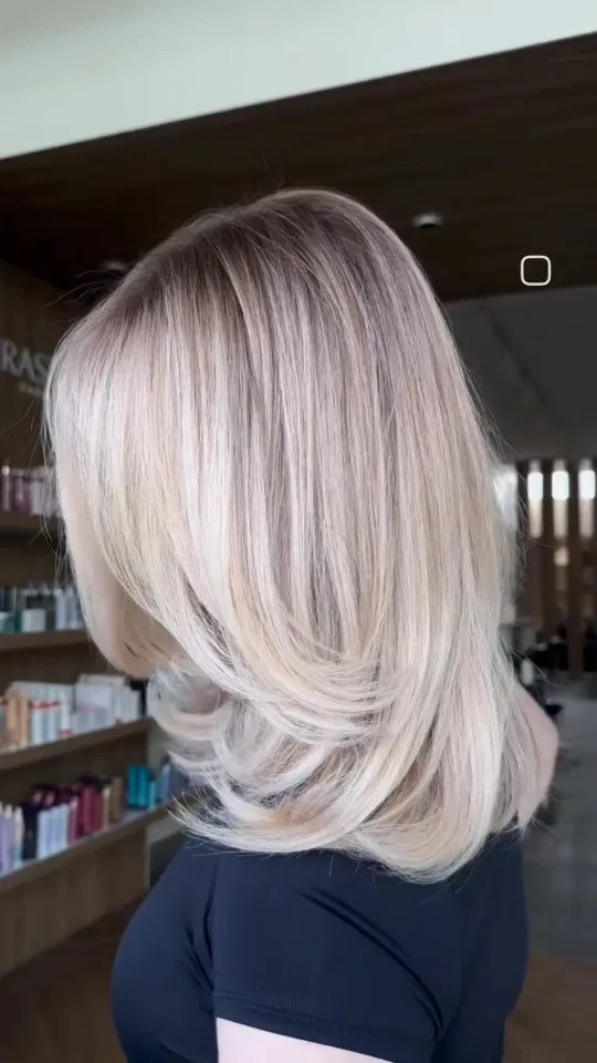 Back view of layered blonde hair against product shelves