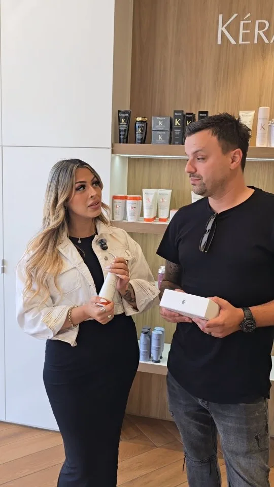 Stylist holding a Kérastase product, consulting at the retail shelf