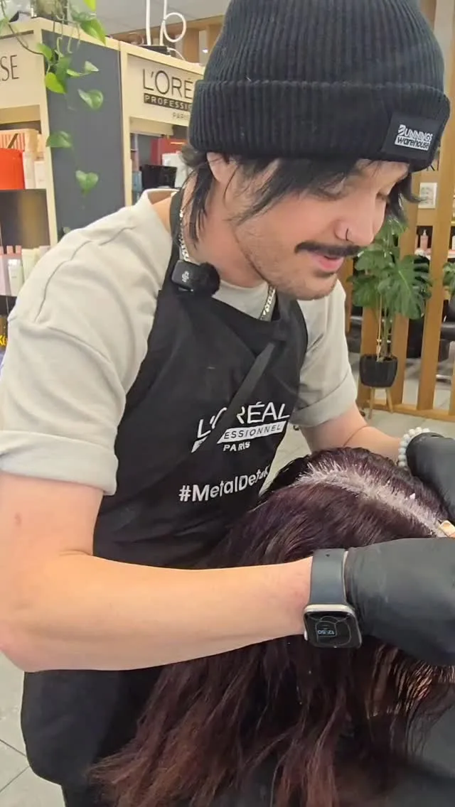 Stylist applying a scalp treatment on a client, L'Oréal Professionnel shelf behind