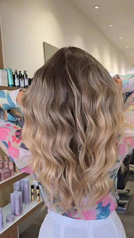 Stylist mid-cut on a client's dark hair, street shopfront window behind